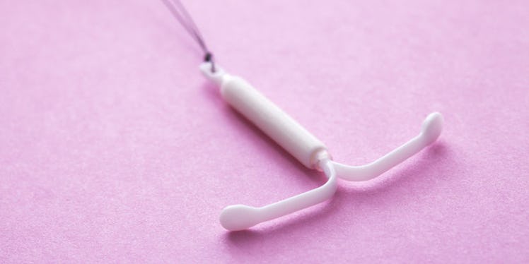 A white IUD placed on a pink surface