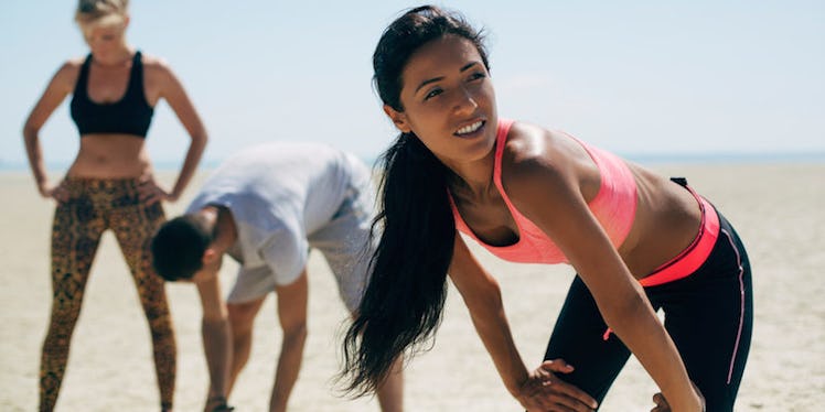 Two women and a man taking a break after jogging, doing a breathing exercise to lower stress levels