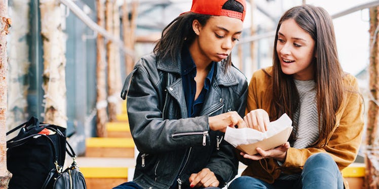Two female friends eating chips from a cartoon box together