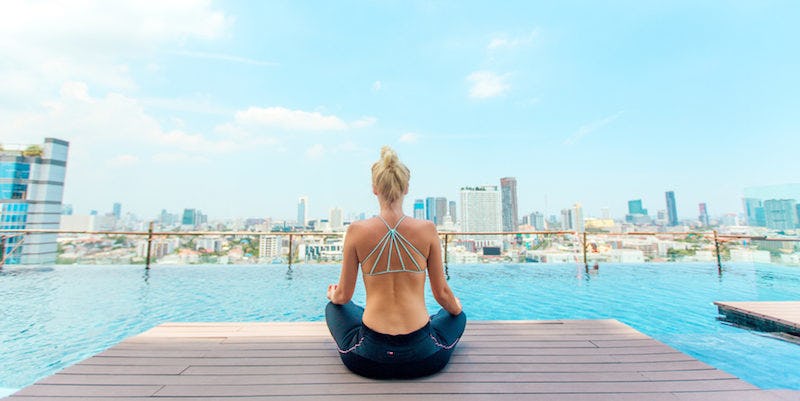 A woman meditating on a dock to reduce holiday stress
