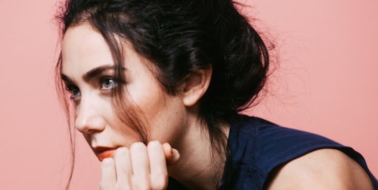 A woman sitting with her hand on her chin, looking into the distance as she is stressed about work