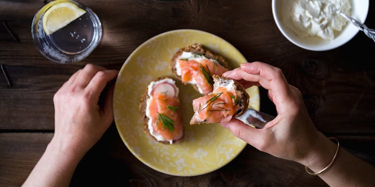 A person taking one of three salmon toast sandwiches from a yellow plate, which can boost your mood