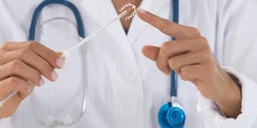 A doctor holding an IUD with a stick before placing it into a woman's body