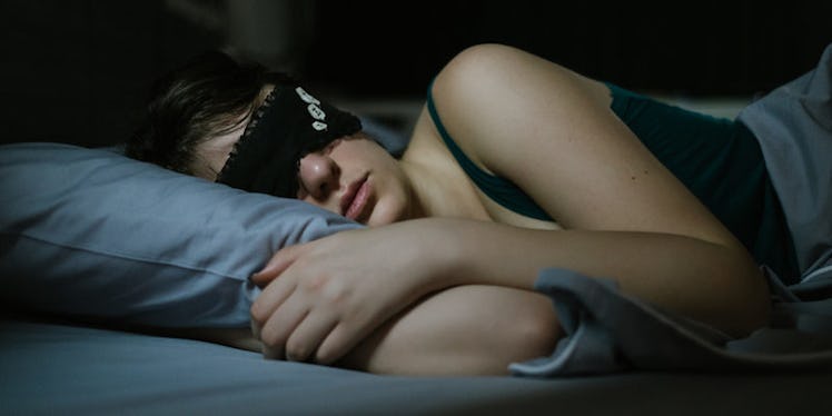 A woman wearing a black sleeping mask, sleeping in blue bed sheets who fell asleep instantly 