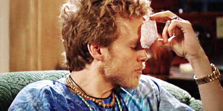 A man holding a healing crystal on his forehead.