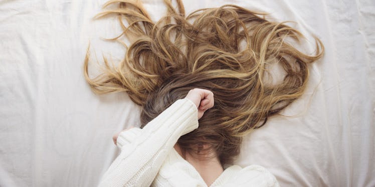 A blonde woman lying on the bed with her hair scattered around.
