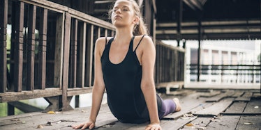 a young woman in a black workout tank top doing stretches
