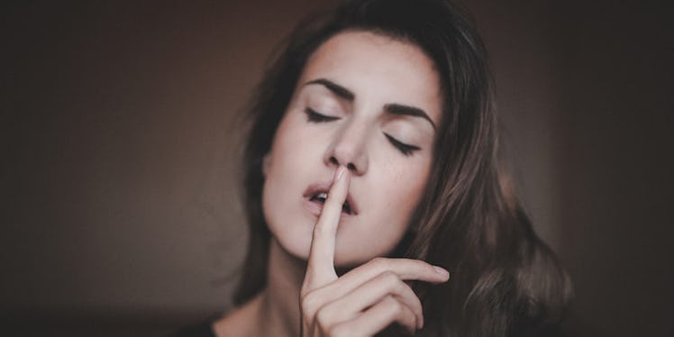 A woman who suffers from anxiety with her eyes closed, covering her lips with her index finger