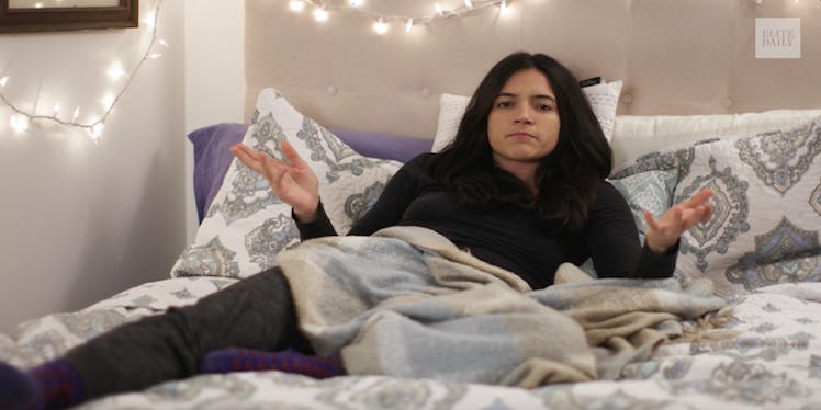 A woman with social anxiety lying in her bed, covered with a blanket
