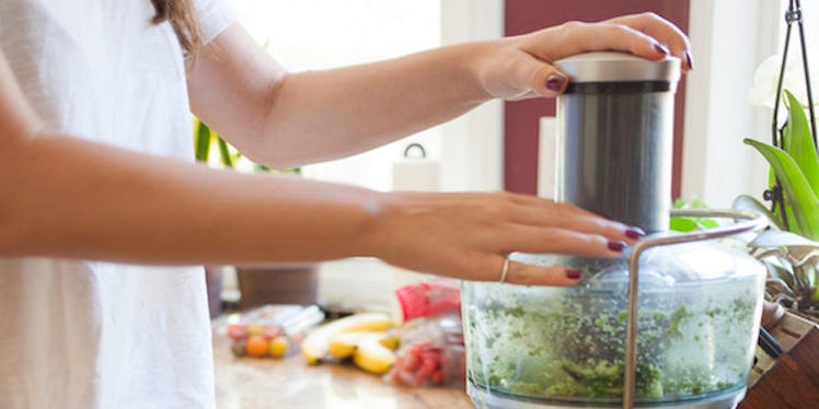 A woman with PCOS in her kitchen blending veggies in a blender