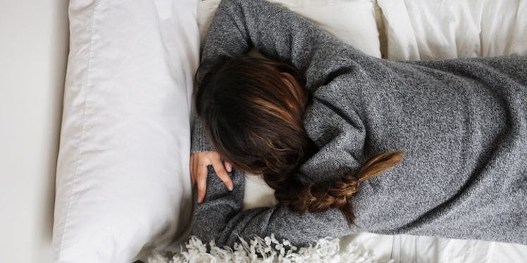A girl buried her face in the sheets while lying on the bed.