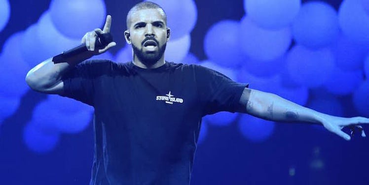 Drake on stage pointing upwards with his index finger while holding a microphone