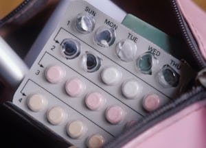 A pack of birth control pills peaking out of a makeup bag