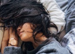 A dark-haired woman sleeping with her hair on her face with her contact lenses in