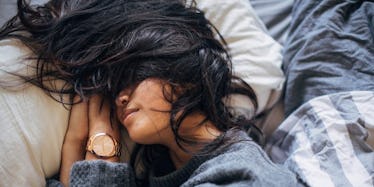 A dark-haired woman sleeping with her hair on her face with her contact lenses in