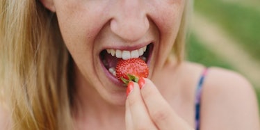 A young lady eating a strawberry