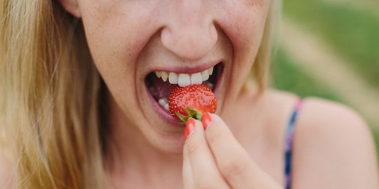 A young lady eating a strawberry