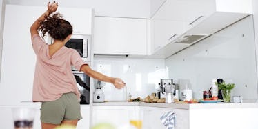 a young woman dancing around her kitchen in shorts.