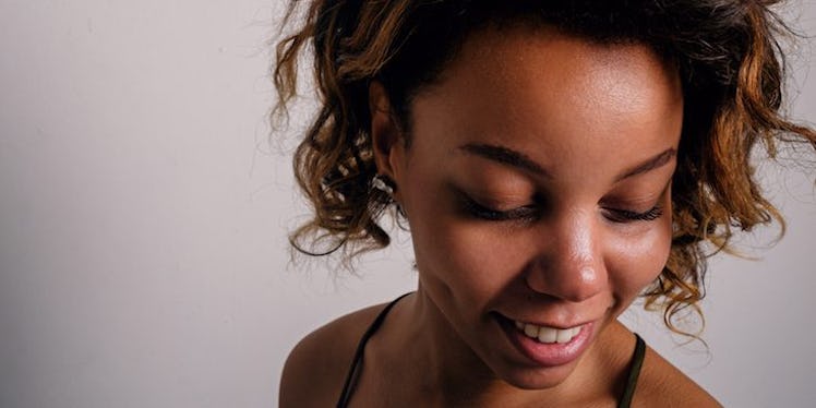 A curly-haired brunette woman smiling, and looking down, who doesn't get stressed