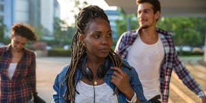 A girl in a white shirt, blue jacket and earphones experiencing back-to-school stress as she approac...