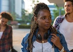 A girl in a white shirt, blue jacket and earphones experiencing back-to-school stress as she approac...
