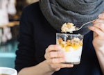 A person grabbing a spoonful of yoghurt and oatmeal as a snack that can help with anxiety