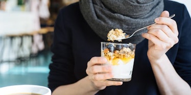 A person grabbing a spoonful of yoghurt and oatmeal as a snack that can help with anxiety