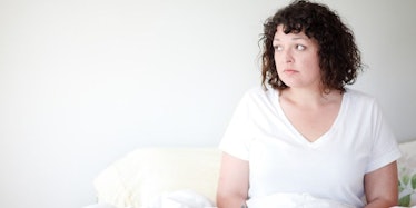 A woman with PCOS sitting on her couch, looking into the distance