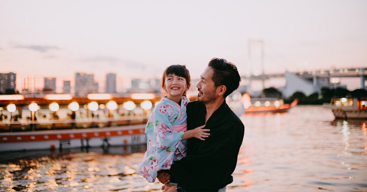 Father holding daughter in front of scenic river view.
