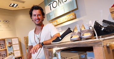 Blake Mycoskie the founder of toms shoes stands in a white shirt in his store smiling