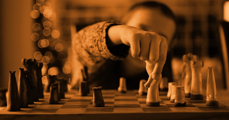 A child making a chess move while standing next to the chess set, pictured in sepia