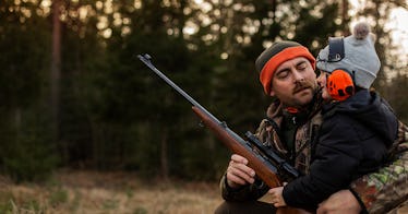 A dad and his daughter on a hunting trip, the daughter is wearing noise-cancelling headphones and th...