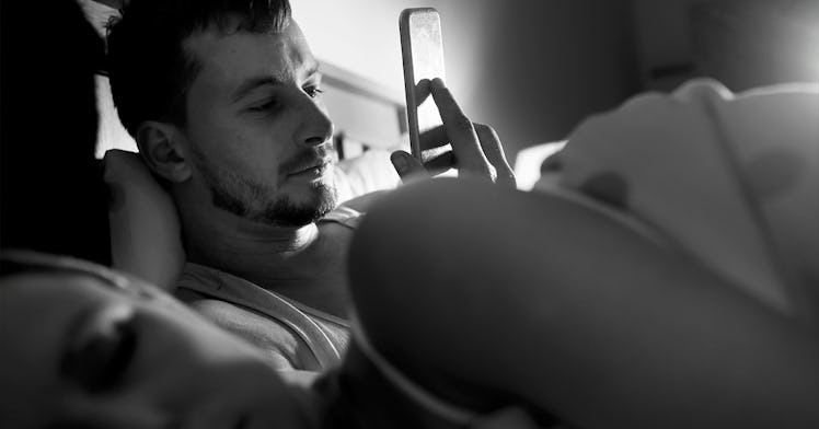 A man pphubbing while in bed with his female partner