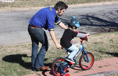 father teaching son to ride bike