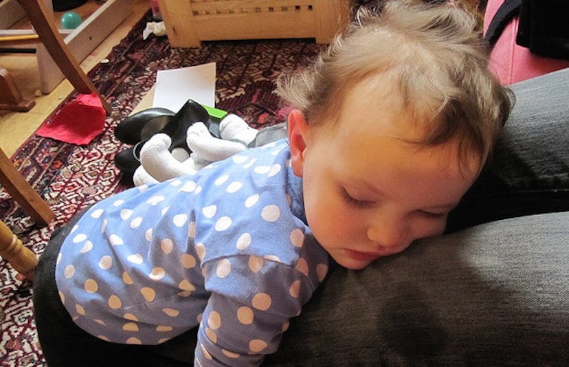 A toddler leaned on the couch and sleeping while standing