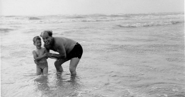 A father and son playing at the beach while standing in knee high level water
