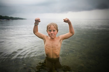 A small boy showing his muscles while in Sebago Lake