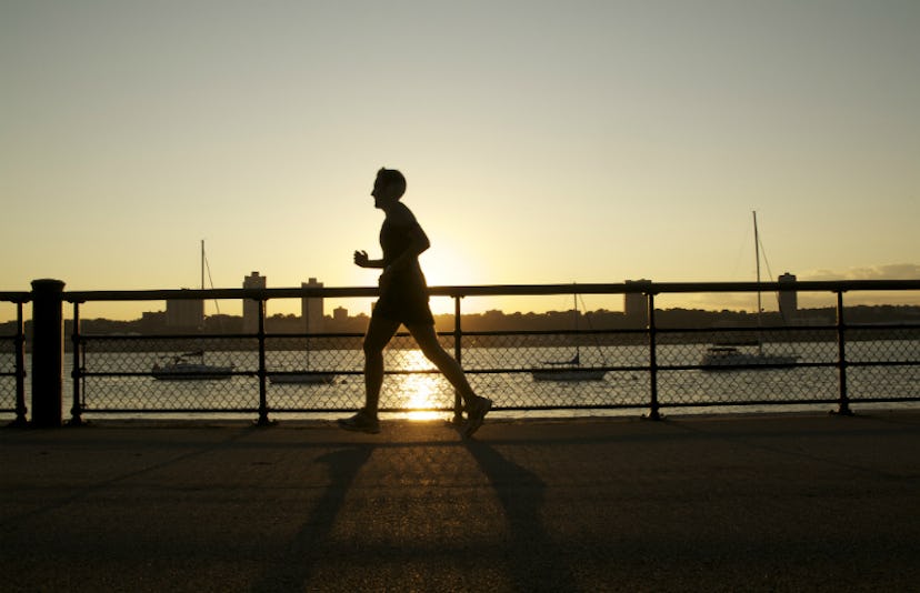 A man jogging next to a river during sunset