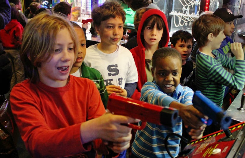 Two boys playing a shooting video game with guns in their hands