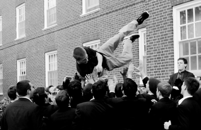 A group of boys throwing their friend in the air during a celebration