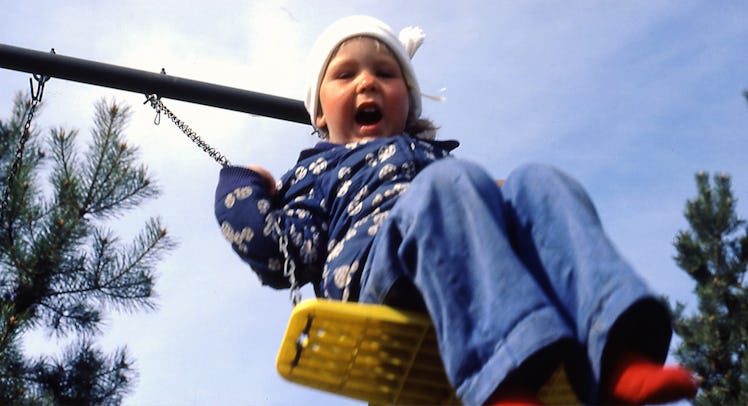 An extroverted toddler yelling while on a swing