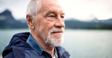 A happy retired man in a navy jacket looking into the distance