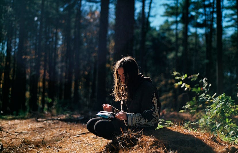 A girl sitting alone in the middle of a forrest