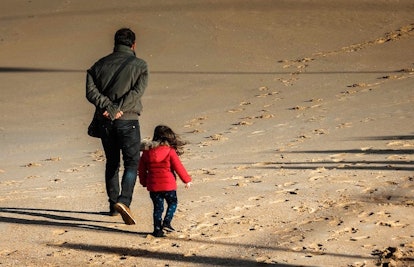 A dad and daughter walking on sand