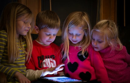 A boy and three girls sitting next to each other and looking into a smartphone who have limited scre...