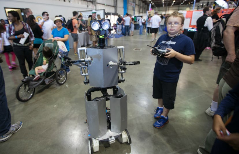 A digitally savvy boy and his robot he has made for a school project and other parents and students ...