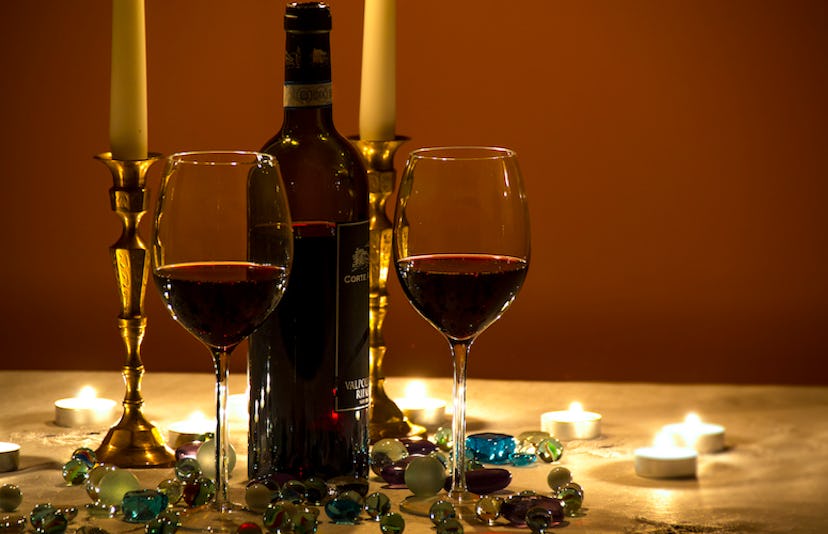 Two glasses of red wine, a bottle and two candles