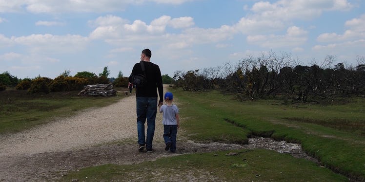 A father and a little son walking down a field together