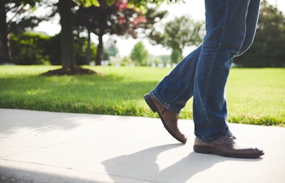 A man walking on concrete in denim jeans and brown boots