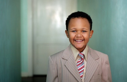 A kid smiling in a suit and a tie 